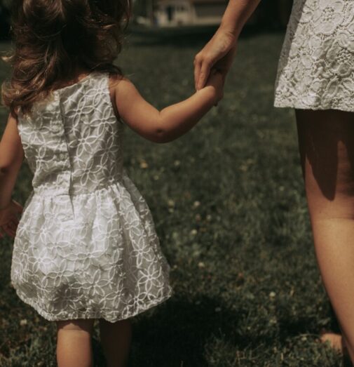 a woman holding the hand of a little girl