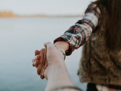 shallow focus photography of man and woman holding hands