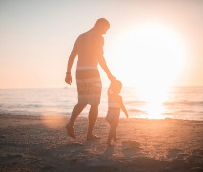 man holding girl heading towards sea