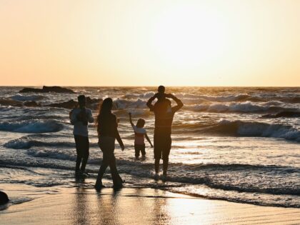 A group of people standing on top of a beach next to the ocean